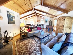 Un vaste espace de vie doté d’un haut plafond en bois, d’un canapé, d’une table basse et d’un baby-foot.