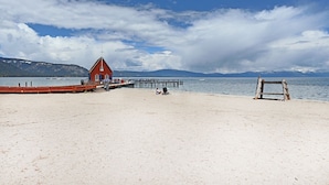 A beach with a red building, a wooden structure, and a pier extending into calm waters. - Chalet Lani - HOT TUB - 3 bedroom, 2 bath - Quiet Location! (Homewood)