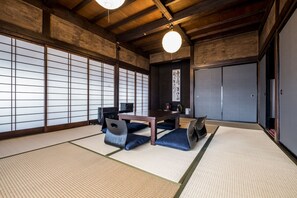 Ett traditionellt japanskt rum med tatamimattor på golvet, ett lågt träbord och blå kuddar.