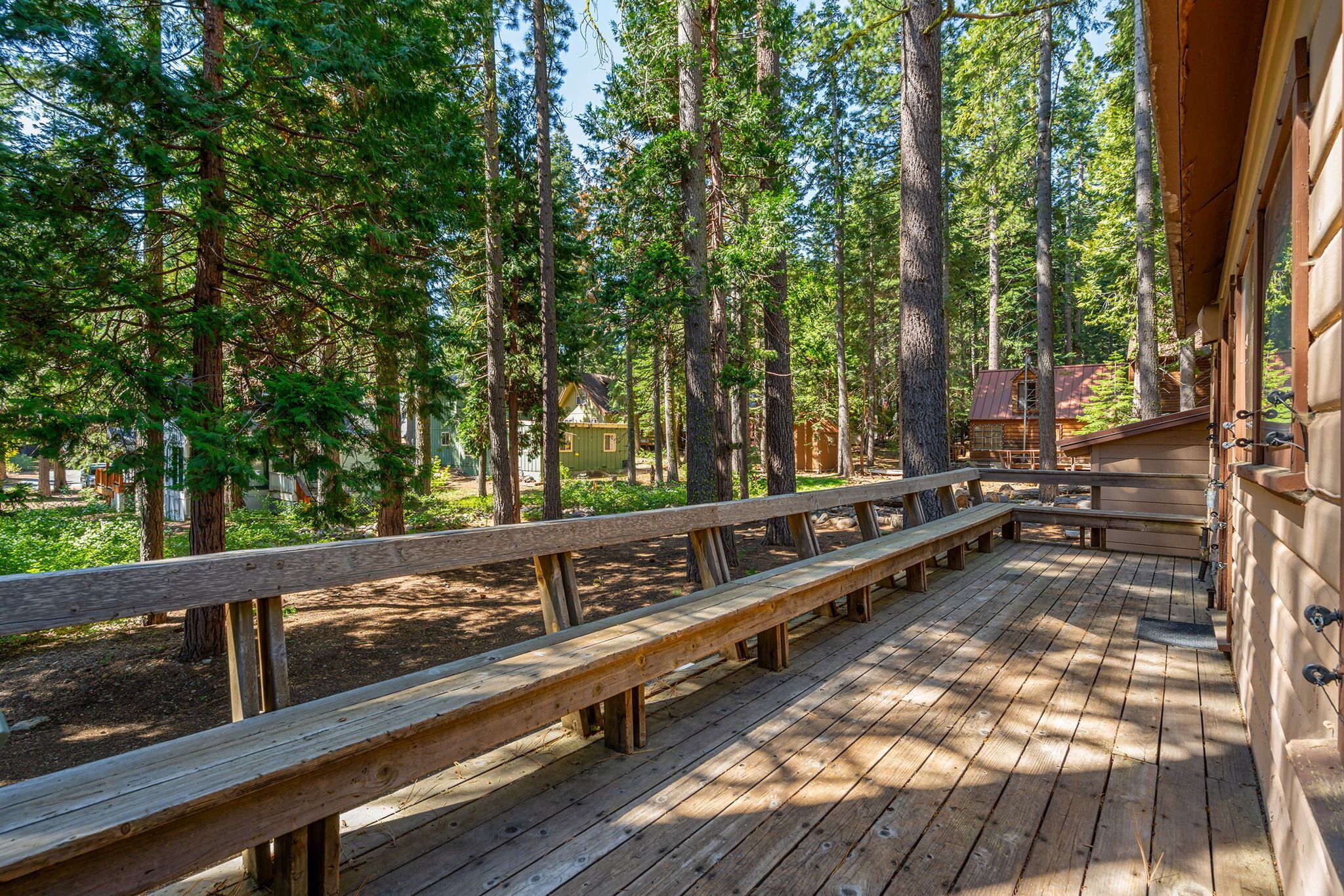 A wooden deck with benches overlooking a forested area.