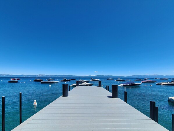 A pier leading into a calm body of water with several boats docked.