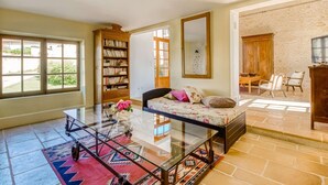 Amplia sala de estar con una mesa de centro de vidrio, un sofá con cojines estampados, una estantería de madera y un espejo grande.