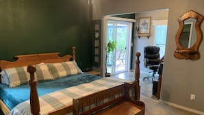 A bedroom with a wooden bed, a nightstand, a chair, and a large window. - Peace and privacy await among the towering Pine Trees. (Bayfield)