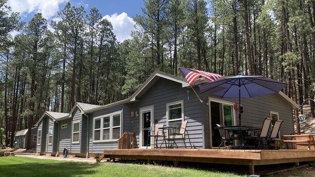 A cabin with a deck, outdoor seating, and an American flag. - Peace and privacy await among the towering Pine Trees. (Bayfield)