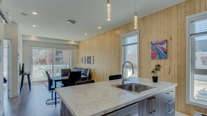 Une cuisine moderne avec un plan de travail en marbre, des murs recouverts de panneaux en bois et une grande fenêtre.