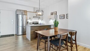Une cuisine moderne dotée d’un réfrigérateur en acier inoxydable, de meubles en bois et d’un îlot central avec des sièges.