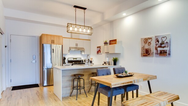 Een moderne keuken met een centraal eiland, roestvrijstalen apparatuur en een hangende lamp.