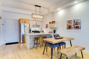 A modern kitchen with a central island, stainless steel appliances, and a hanging light fixture. - L'île-Do | condos neufs sur l'ile d'Orléans, The Snowflake - 702 (Saint-Pierre-de-l'Île-d'Orléans)