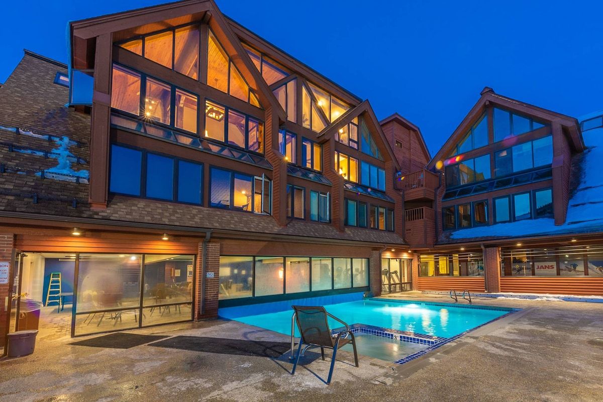 A modern building with a swimming pool, large windows, and a brick facade.