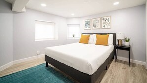 Un dormitorio con cama, mesita de noche, ventana y decoración en la pared.