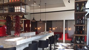 Een moderne bar met een marmeren aanrecht, zwarte barstoelen en een achtergrond van bakstenen.