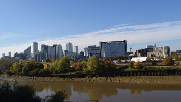 Een stadszicht met moderne gebouwen en een rivier op de voorgrond.