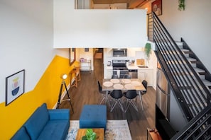 A modern apartment with a dining area, kitchen, and a staircase.