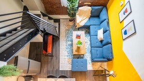 Uma sala de estar moderna com um sofá azul, uma mesa de centro de madeira e uma escada.