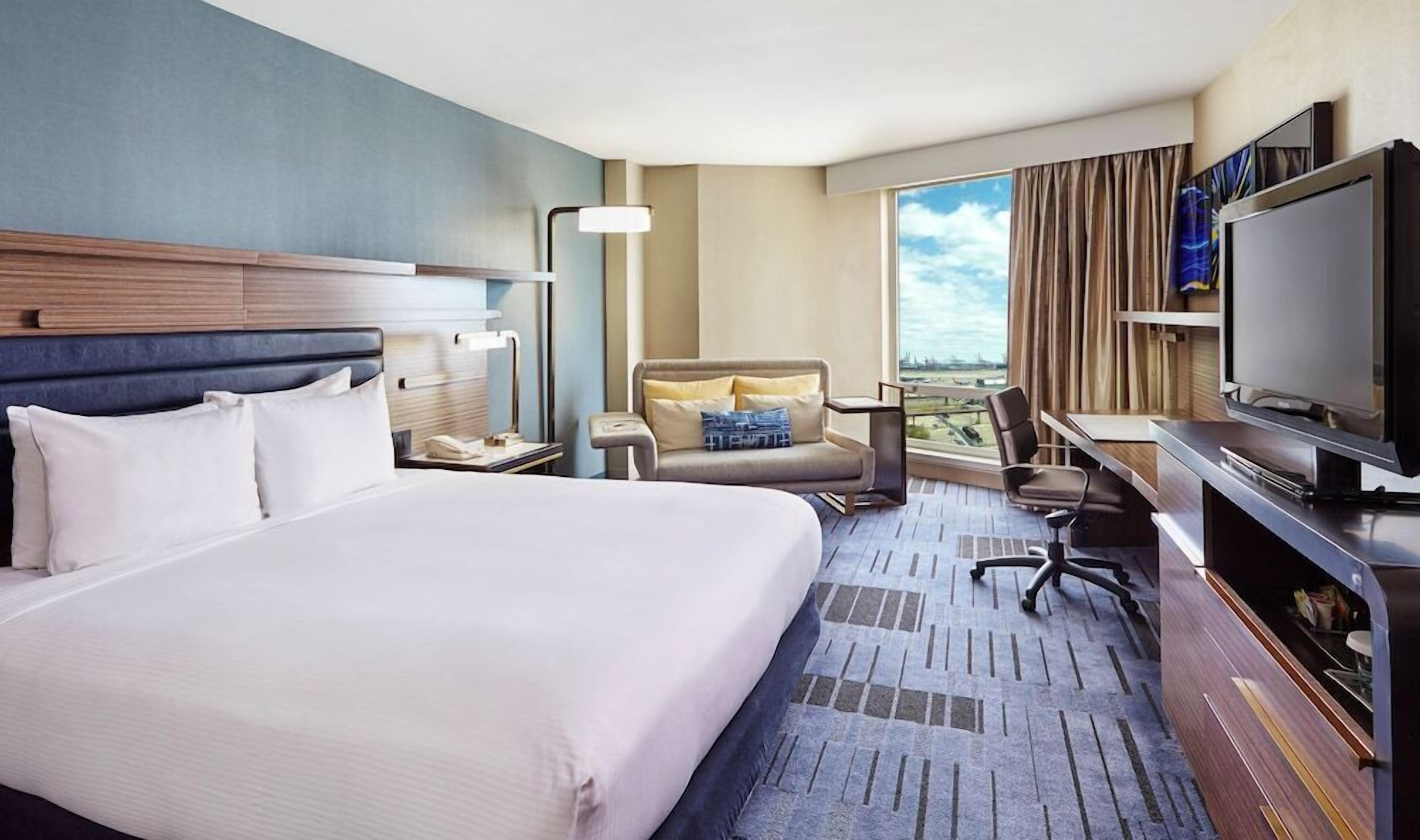 Une chambre d’hôtel avec un grand lit, un bureau, une chaise, une télévision et une vue sur l’extérieur.