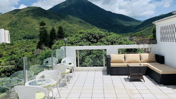 Une terrasse avec des sièges extérieurs, une vue sur une montagne et un bâtiment en arrière-plan.