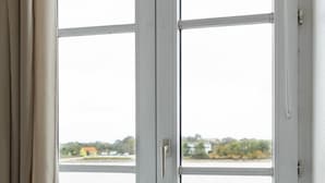 Una ventana con vista a una playa y una casa al otro lado del agua.