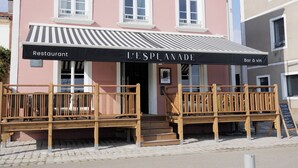 Un edificio rosa con toldo negro que dice "L'ESPLANADE Bar à vin".