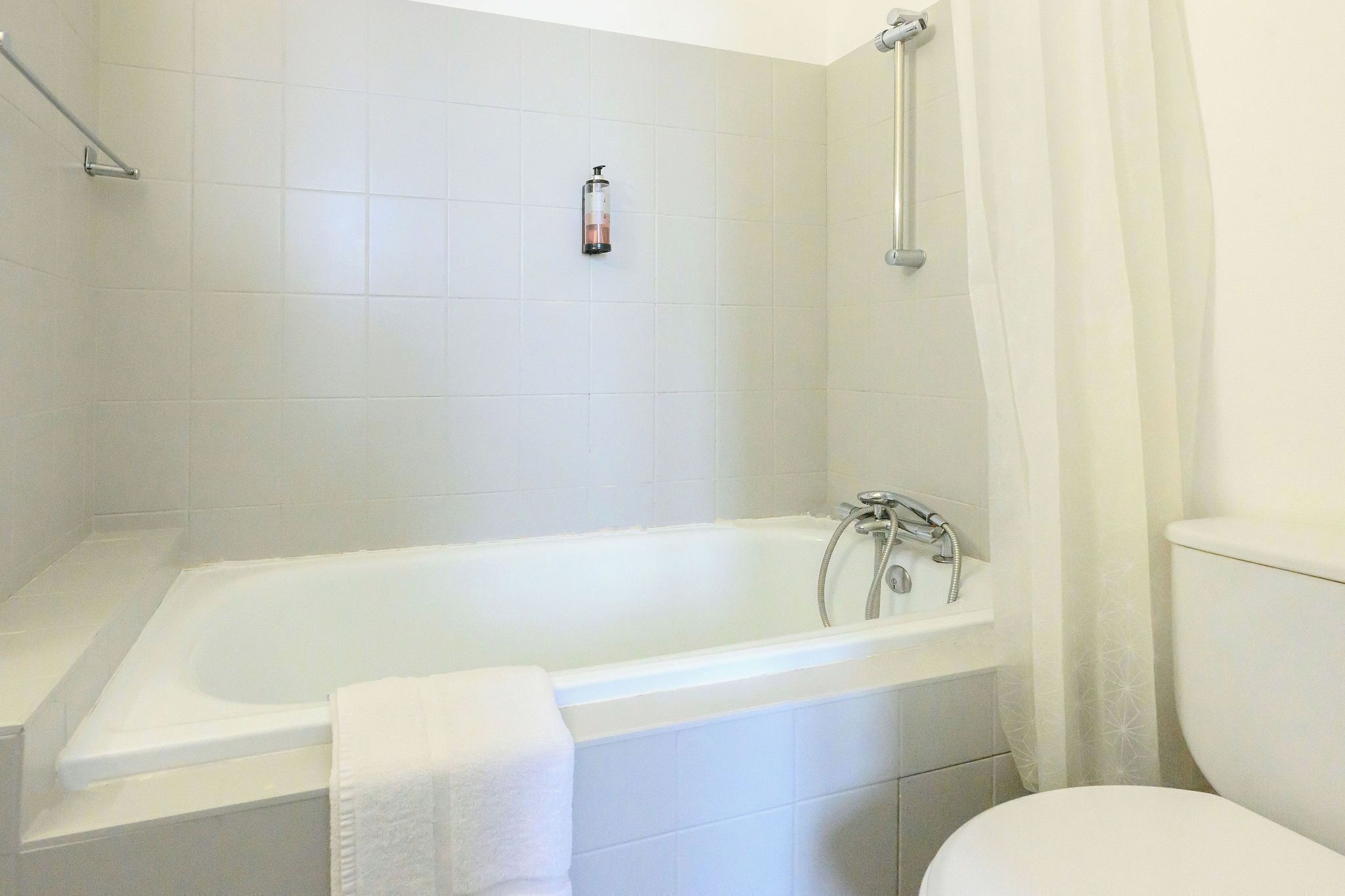 A bathroom with a white bathtub, a toilet, and a shower area.