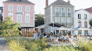 Un hotel con letrero, zona de estar exterior con sombrillas y un jardín.