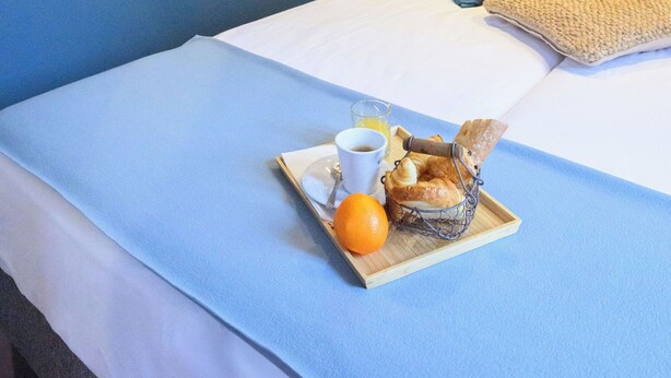 Una cama bien hecha con una bandeja de desayuno, una taza y una naranja.
