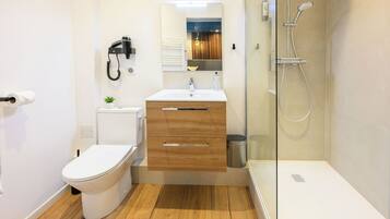 Un baño moderno con inodoro, lavamanos y ducha.