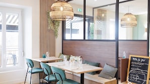 Un comedor moderno con una mesa de madera, sillas verdes y lámparas de mimbre colgantes.