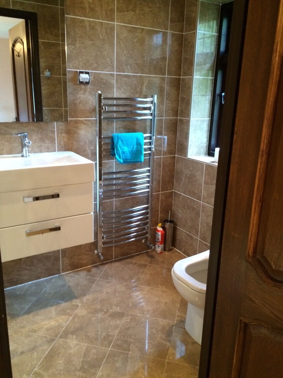 Un baño con lavamanos, espejo, toallero y retrete.