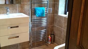 Un baño con lavamanos, espejo, toallero y retrete.