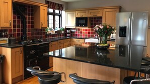 A modern kitchen with wooden cabinets, a stainless steel refrigerator, and a central island with bar stools. - Striking home IN Stratford-on-Avon, a stroll to all key attractions.Sleeps 14-15 (Stratford-upon-Avon)