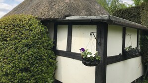 A traditional thatched-roof structure with a white and black exterior, surrounded by lush greenery. - Striking home IN Stratford-on-Avon, a stroll to all key attractions.Sleeps 14-15 (Stratford-upon-Avon)
