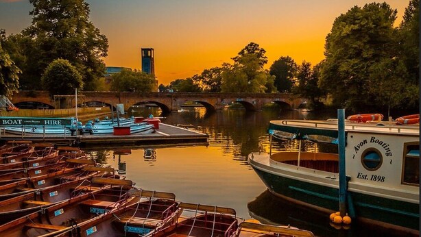 A row of wooden rowboats docked at a marina with a bridge in the background. - Striking home IN Stratford-on-Avon, a stroll to all key attractions.Sleeps 14-15 (Stratford-upon-Avon)