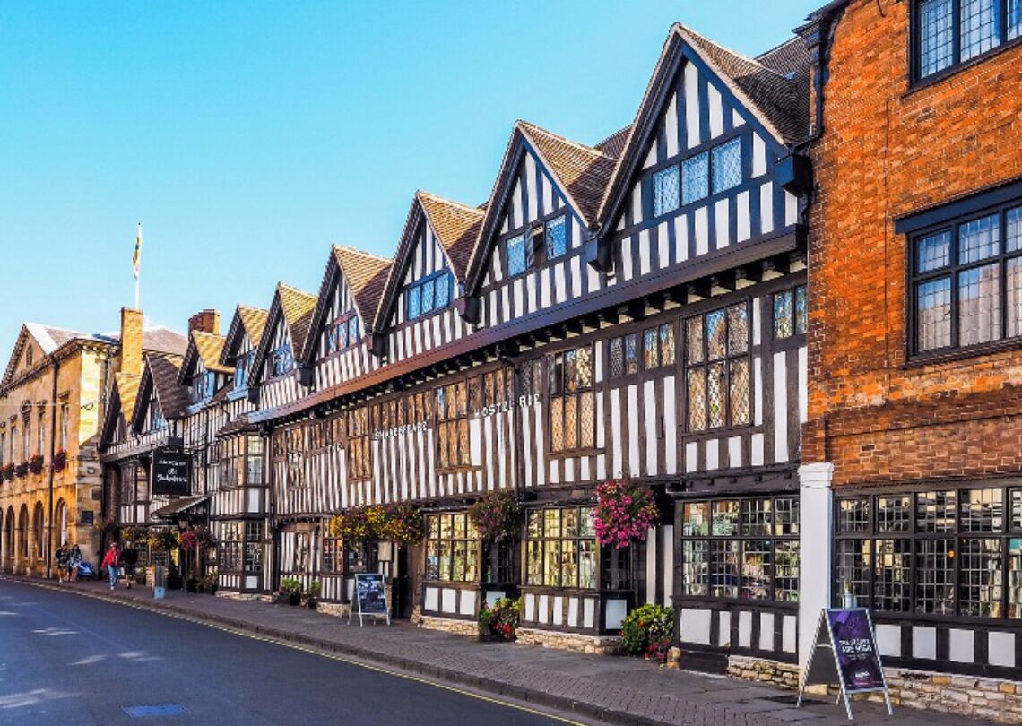 A row of traditional half-timbered buildings with large windows and a signboard.