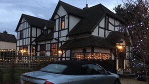 A traditional Tudor-style building with a car parked in front. - Striking home IN Stratford-on-Avon, a stroll to all key attractions.Sleeps 14-15 (Stratford-upon-Avon)