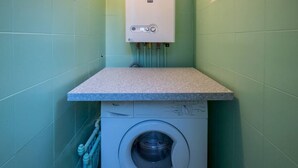 A compact laundry area with a washing machine and a water heater.