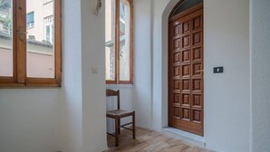 A hallway with a wooden door, a window, and a chair. - Picabon Apartment with AC Balcony (Monterosso al Mare)