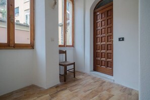 A hallway with a wooden door, a window, and a chair.