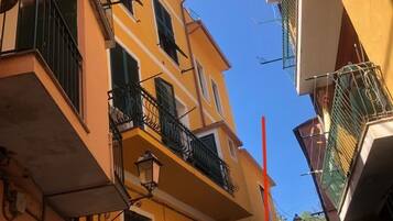 A narrow street with yellow buildings, balconies, and a clear blue sky.
