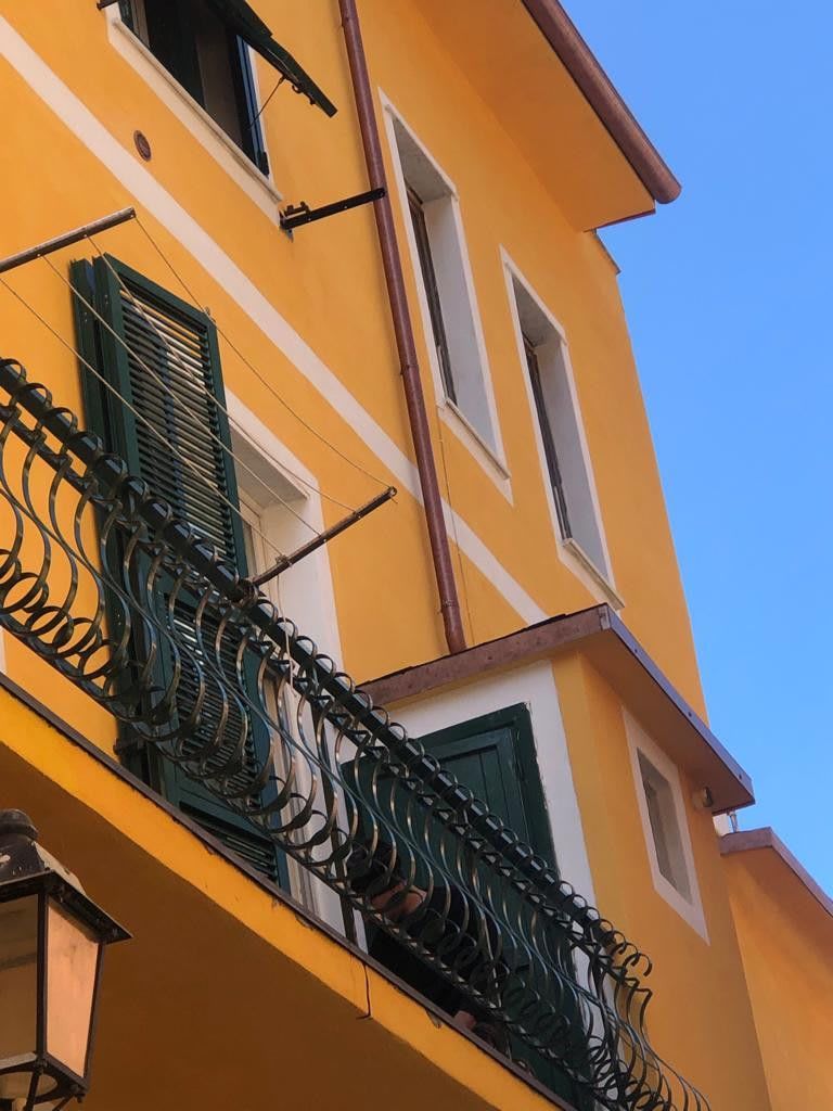 A yellow building with a balcony, a window, and a door.