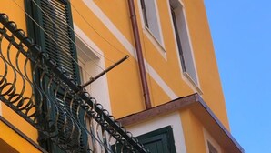 A yellow building with green shutters and a metal balcony railing.