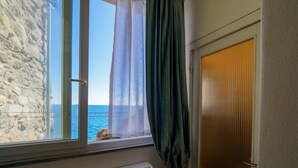 A room with a window overlooking the sea, a stone wall, and a window blind. - Ventu de Ma Sea View Room #3 (Vernazza)