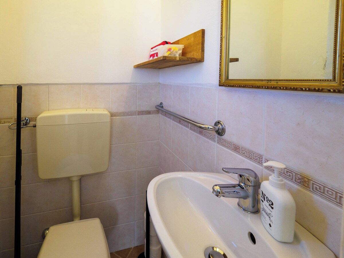 Een badkamer met toilet, wastafel en een plank met toiletartikelen.