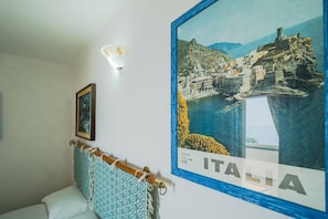 Ein Schlafzimmer mit einem Bett, einem gerahmten Bild, einer Wandleuchte und einem großen Poster von Italien.