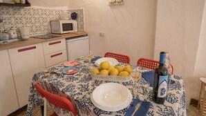 A kitchen with a dining table set for two, a microwave, and a fruit bowl.