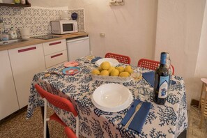 A kitchen with a dining table set for two, a microwave, and a fruit bowl.