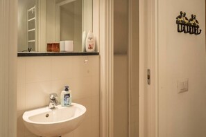 Un baño con un lavabo blanco, un espejo y artículos de tocador sobre la encimera.