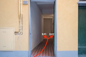 Ein Flur mit rotem Teppich, der zu zwei Räumen mit den Schildern R#1 und R#2 führt.