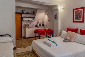 Una habitación pequeña con cama, kitchenette y zona de comedor.