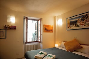 Une chambre d’hôtel avec un lit, une fenêtre donnant sur un beau paysage, un tableau au mur et une lampe.