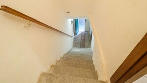 Una escalera con barandilla de madera que lleva a una puerta con felpudo decorado.